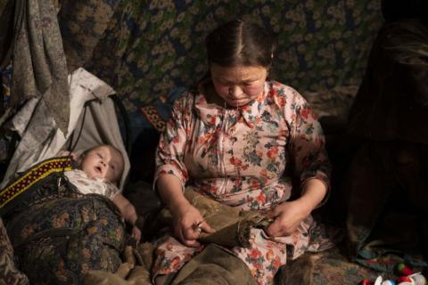 Visuel de l'exposition "EOP, Espaces d'oeuvres photographiques", représentant une femme Nenets cousant des habits en peaux de rennes.
