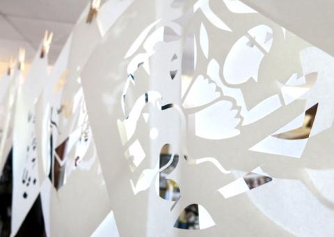 Visuel de l'exposition "Papiers percés" qui représente des feuilles de papiers attachées à un fil à linge, dans lesquelles sont découpées diverses formes.